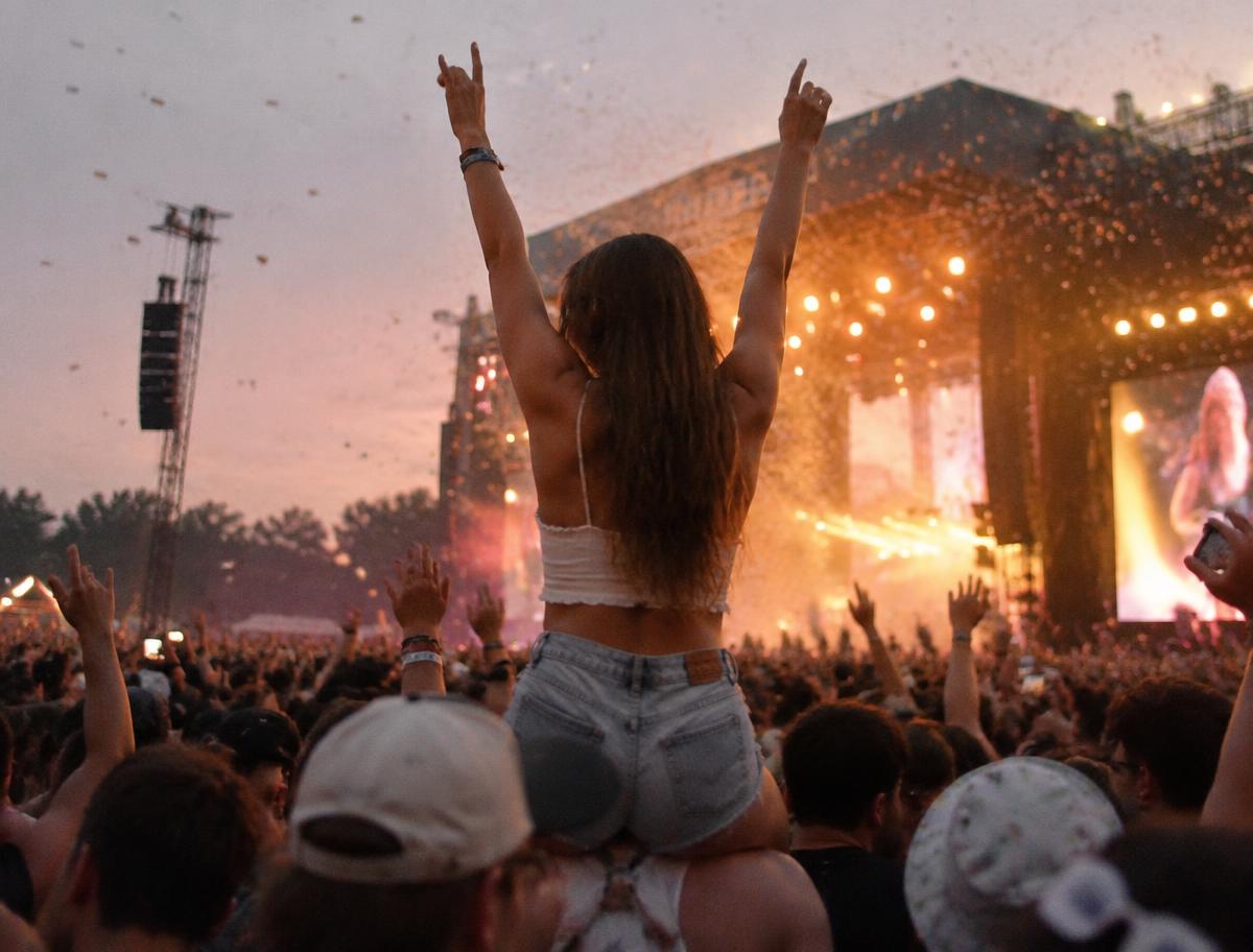 Chica a hombros en un festival de música al atardecer