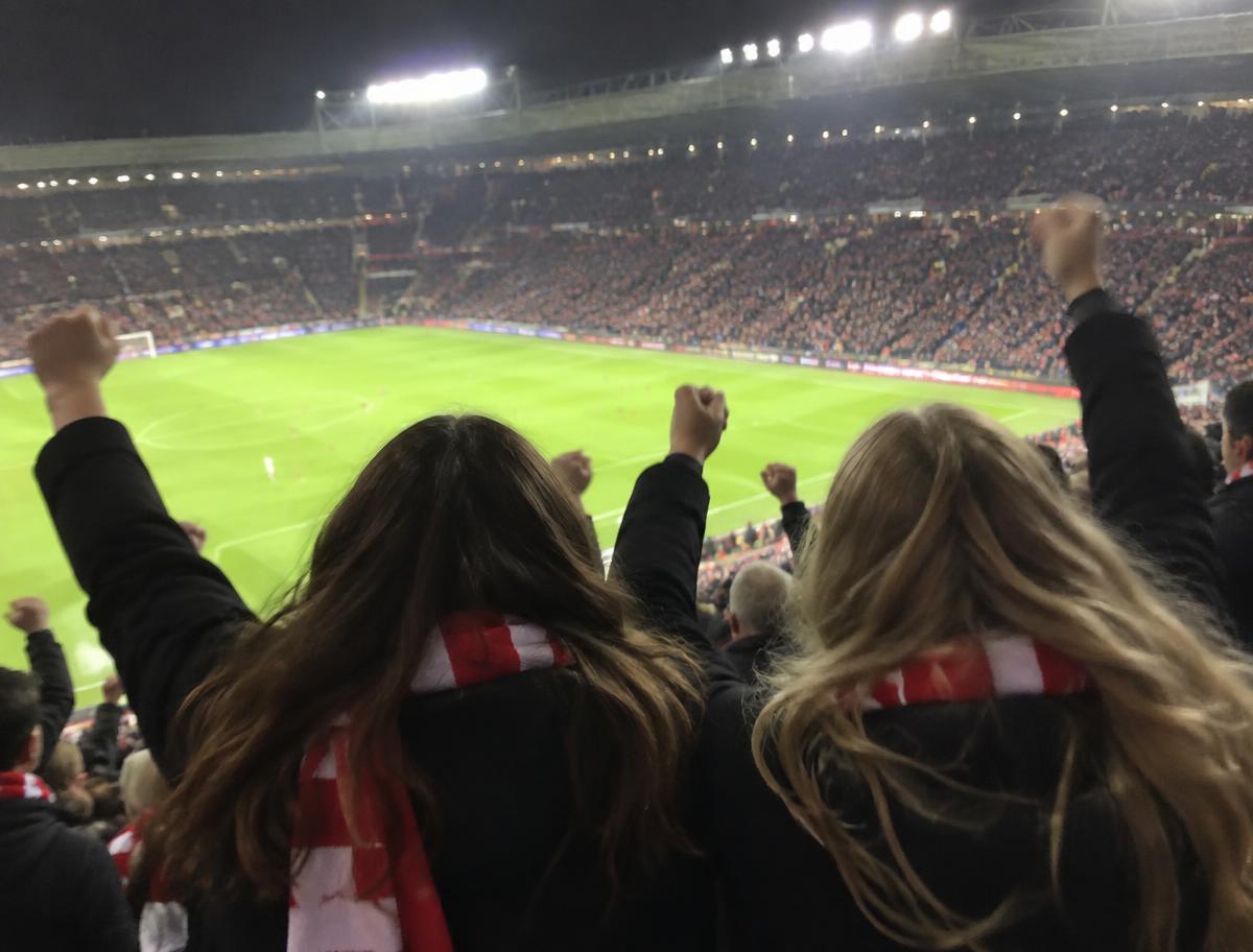 Dos amigas con bufanda celebrando un gol en la grada