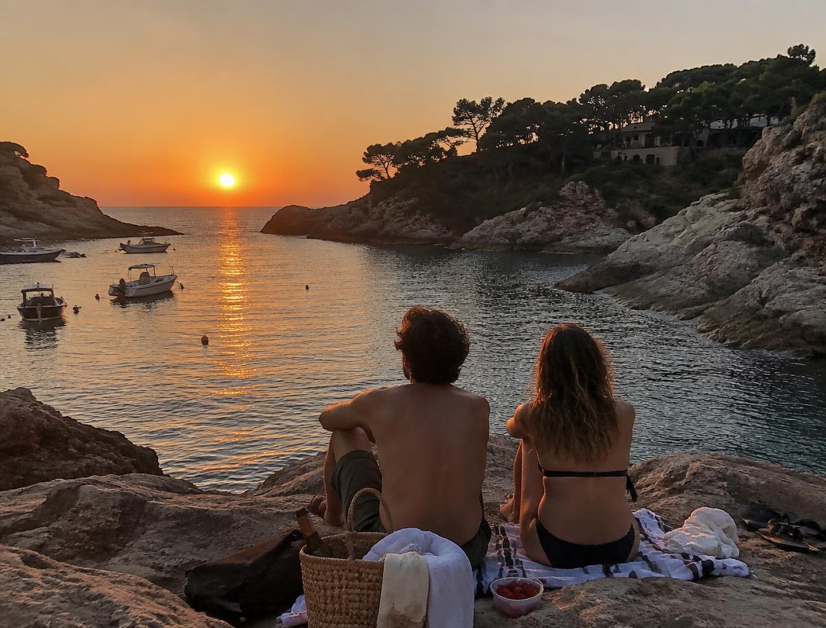 Pareja viendo el atardecer en una cala de la Costa Brava