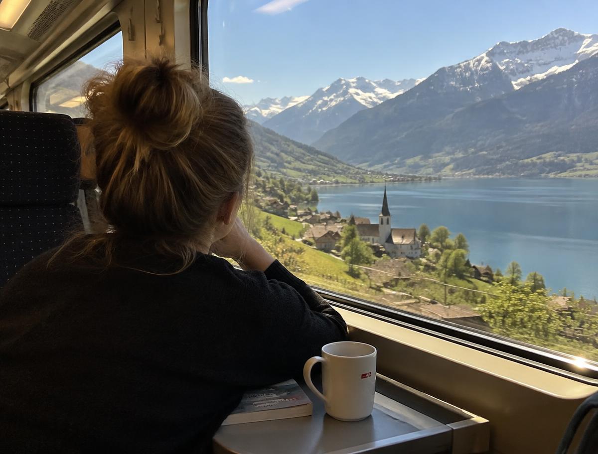 Viajera mirando lagos y montañas desde la ventana de un tren